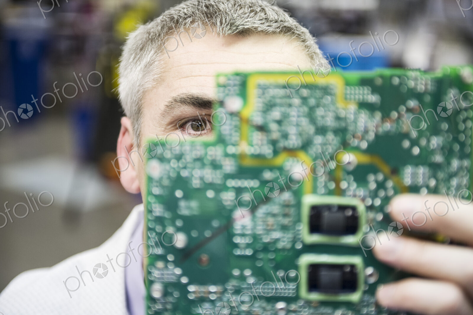 A caucasian male technician examinging a circuit board in a technical research and…
