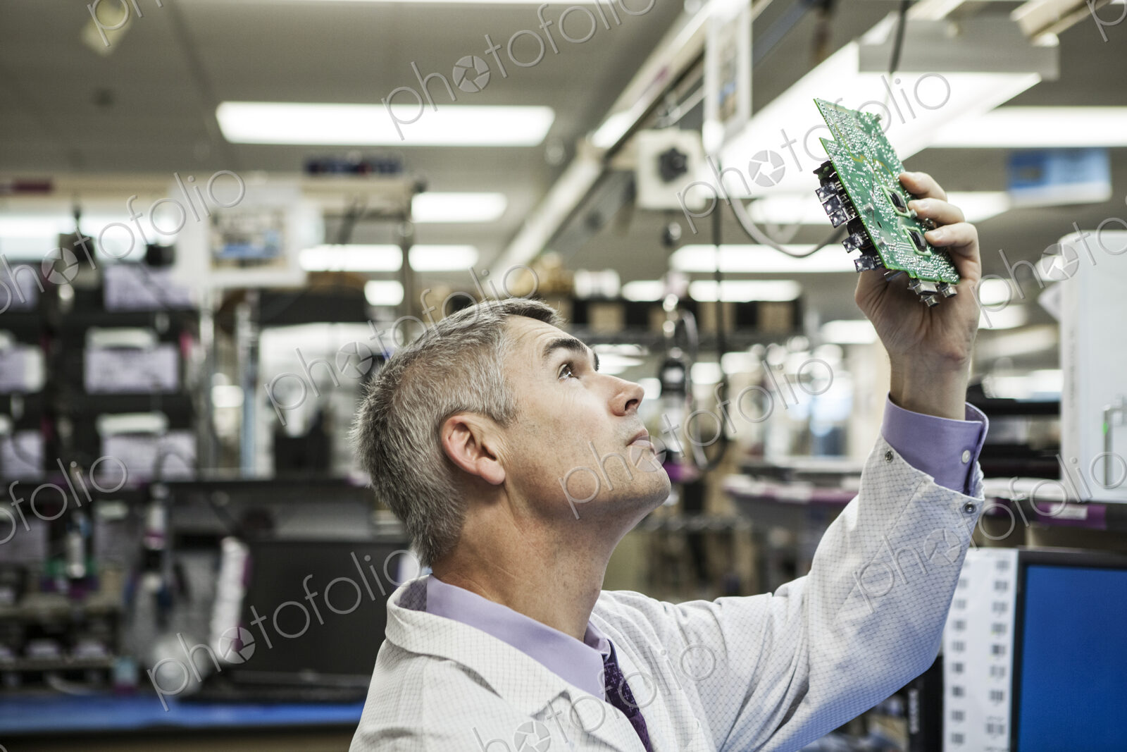 A caucasian male technician examining a circuit board in a technical research and…