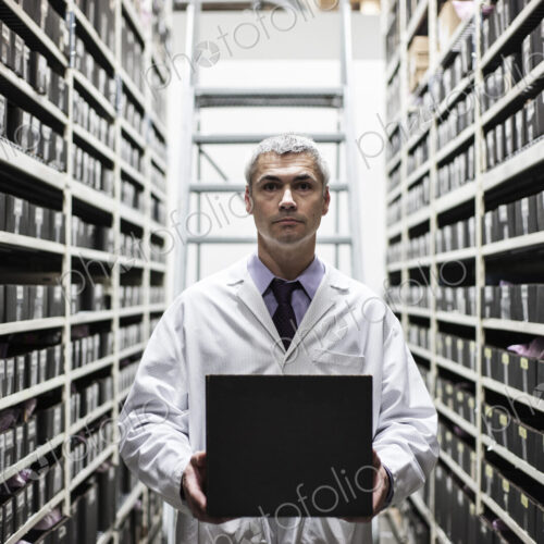 A caucasian male technician working on a laptop combuter among racks of machine parts A caucasian male technician working on a laptop combuter among racks of machine parts