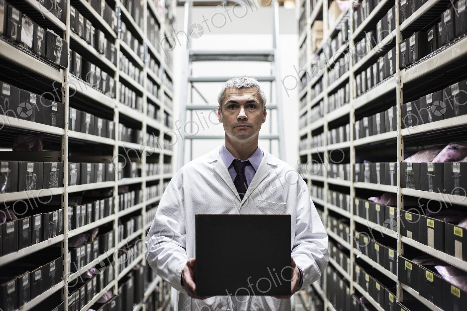 A caucasian male technician working on a laptop combuter among racks of machine parts