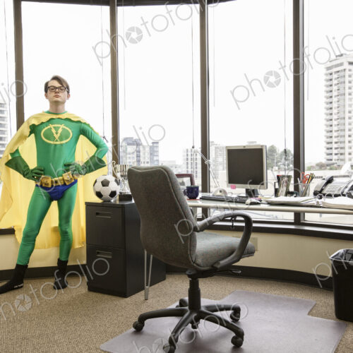 A caucasian man office super hero stands at his office window pondering his next move. A caucasian man office super hero stands at his office window pondering his next move.