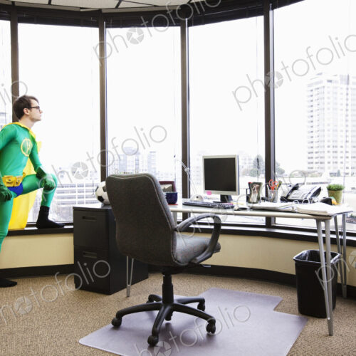 A caucasian man office super hero stands at his office window pondering his next… A caucasian man office super hero stands at his office window pondering his next…