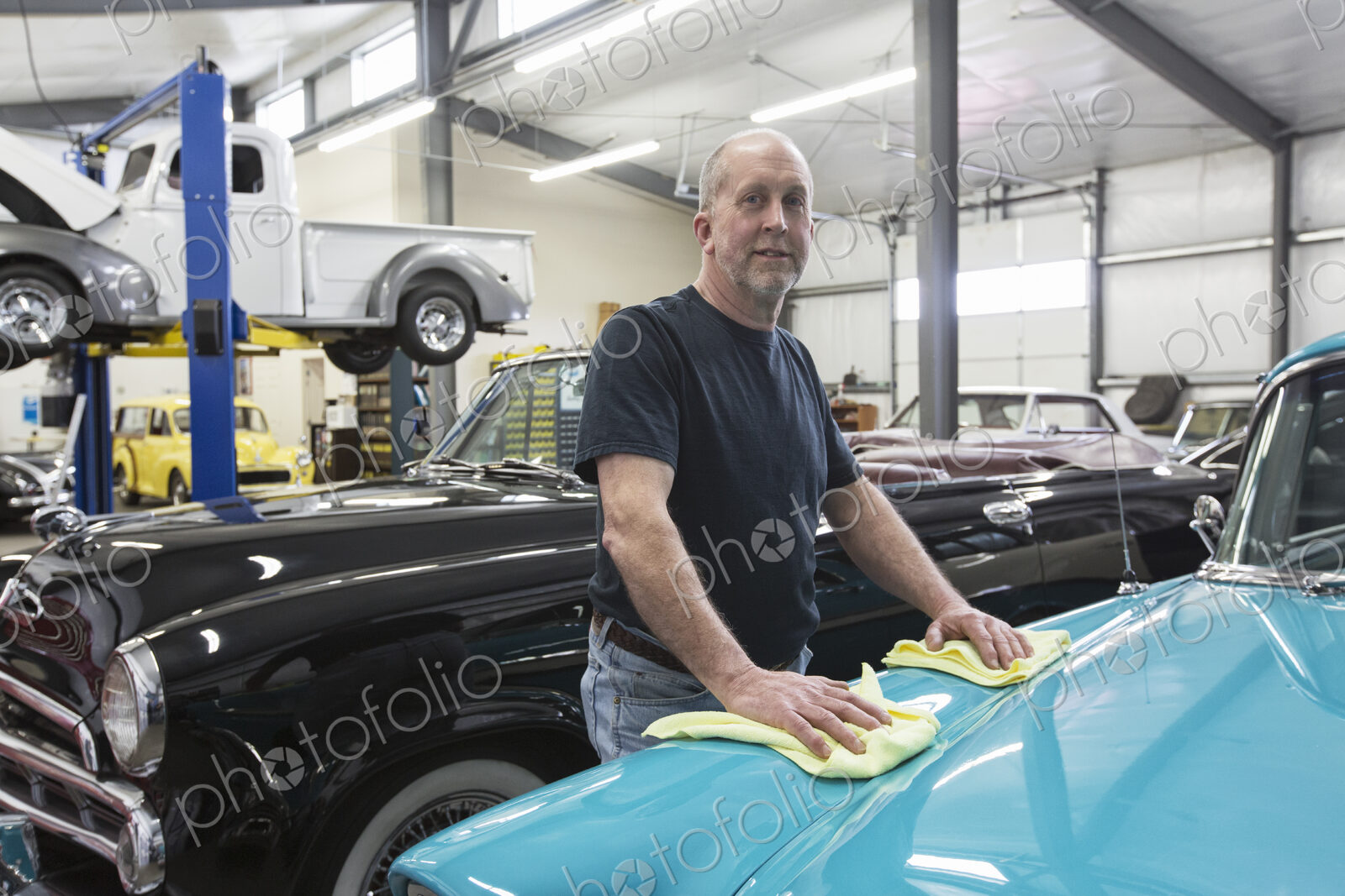 A caucasian senior male car mechnic in ihs classic car repair shop.