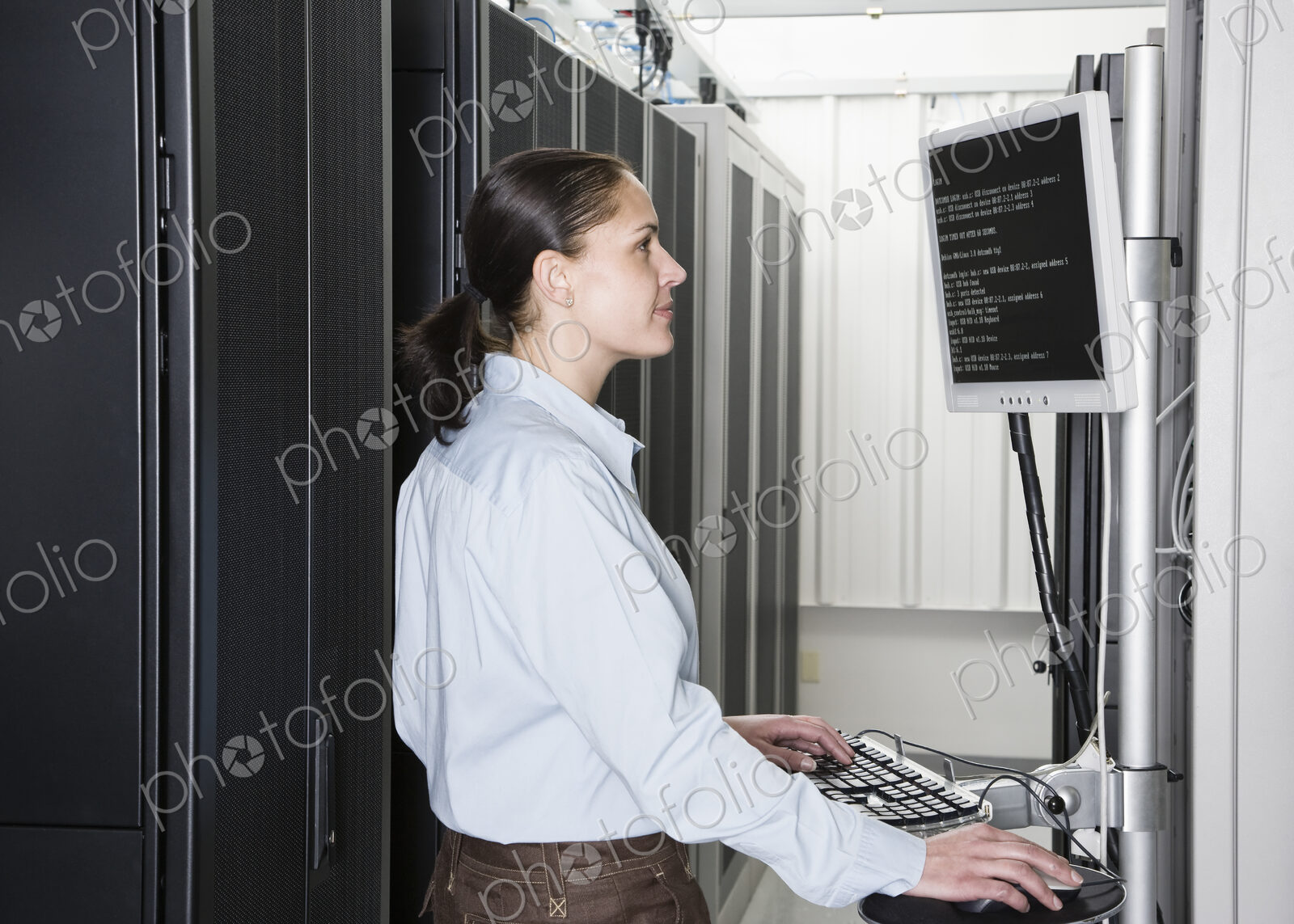 A caucasian woman computer technician working on servers in a computer server farm.