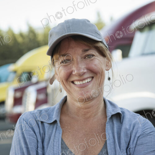 A caucasian woman truck driver near her truck parked in a parking lot of a truck stop. A caucasian woman truck driver near her truck parked in a parking lot of a truck stop.
