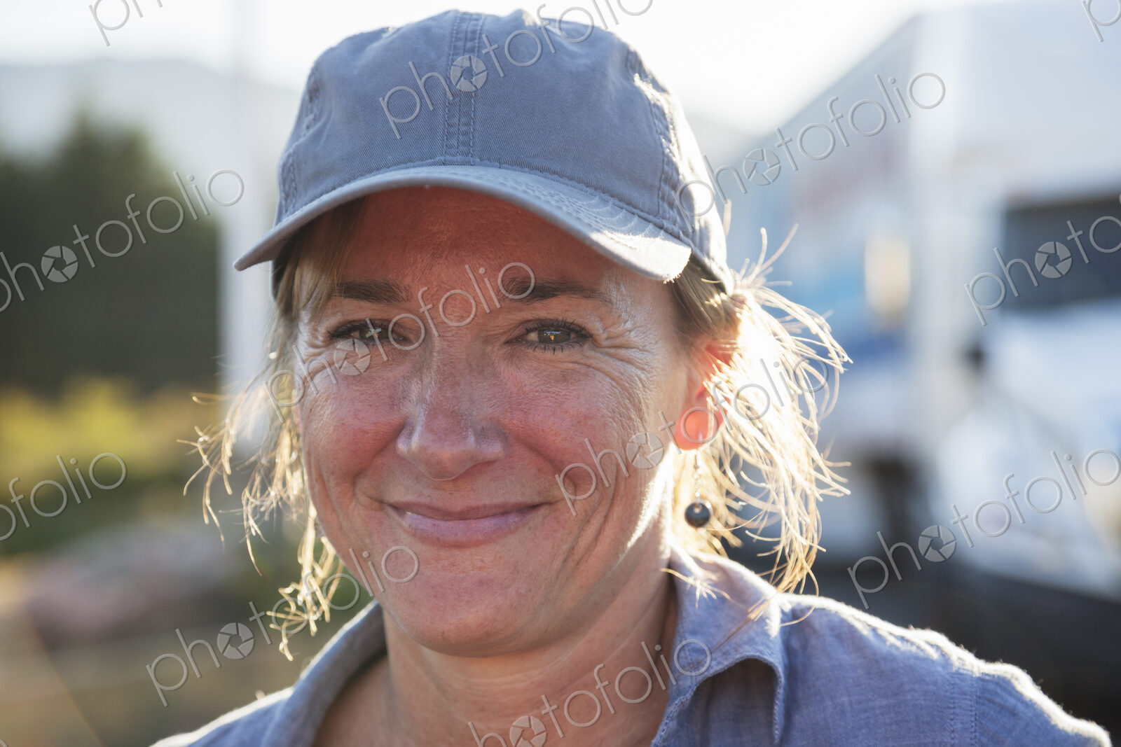 A caucasian woman truck driver near her truck parked in a parking lot of a truck stop.