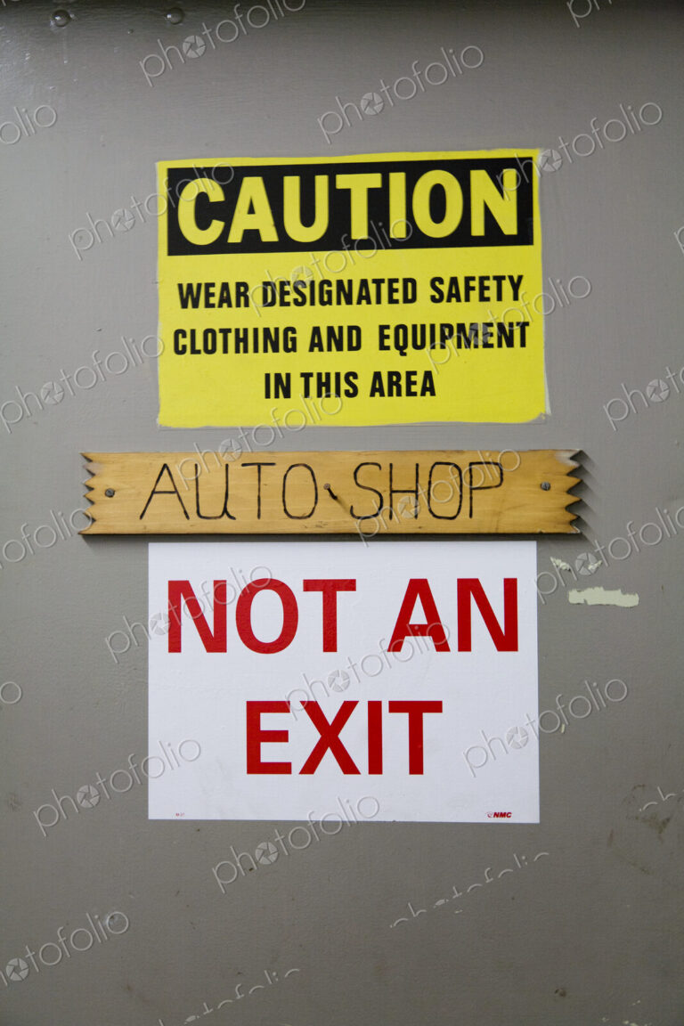 A caution warning sign on a door to an auto-shop, warning, Not An Exit, in red lettering.