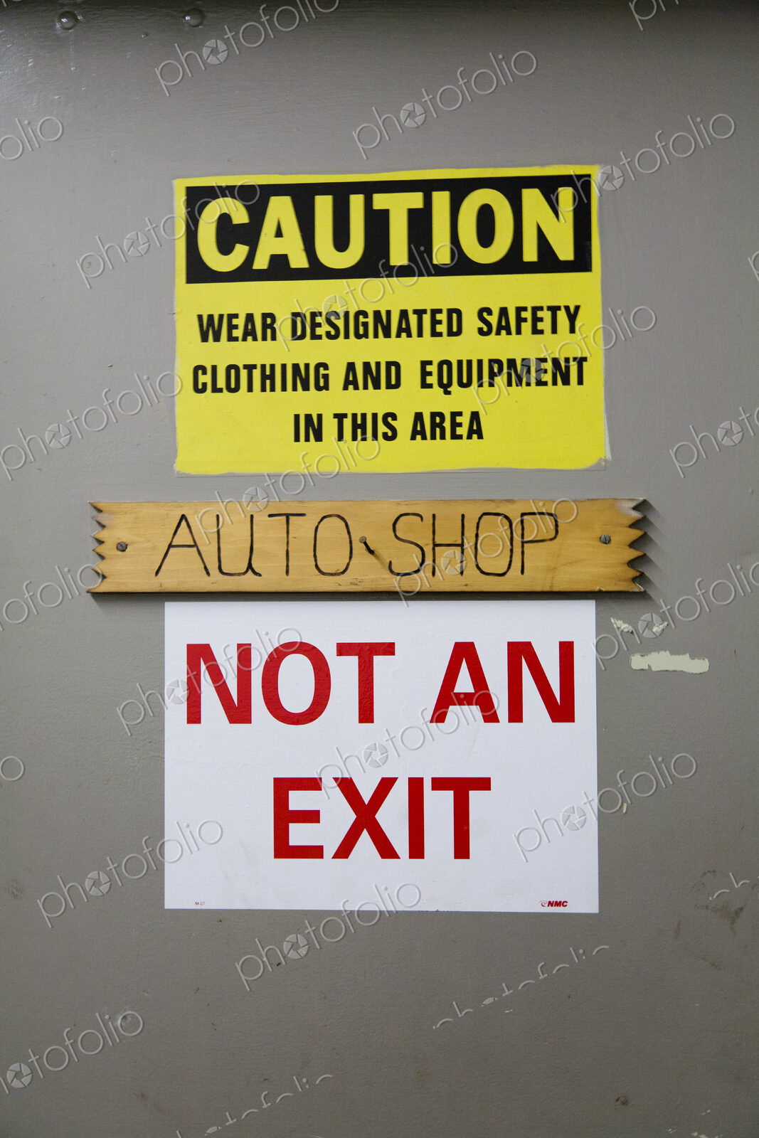 A caution warning sign on a door to an auto-shop, warning, Not An Exit, in red lettering.