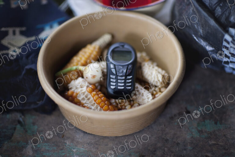 A cell phone,mobile communications,a handset or telephone,in a bowl of maize kernels.
