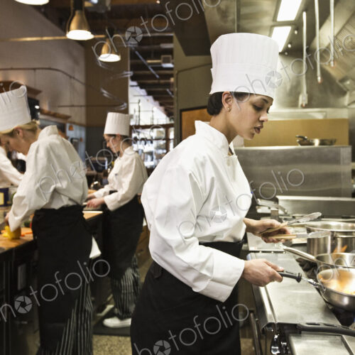 A chef and students at a cookery class in a commercial kitchen A chef and students at a cookery class in a commercial kitchen