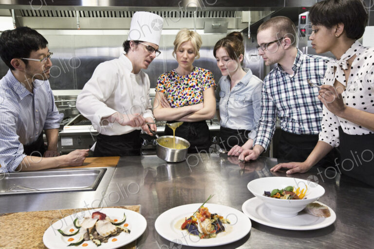 A chef and students at a cookery class in a commercial kitchen