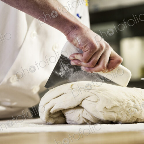 A chef dividing up bread dough into sections on a floured worktop. A chef dividing up bread dough into sections on a floured worktop.