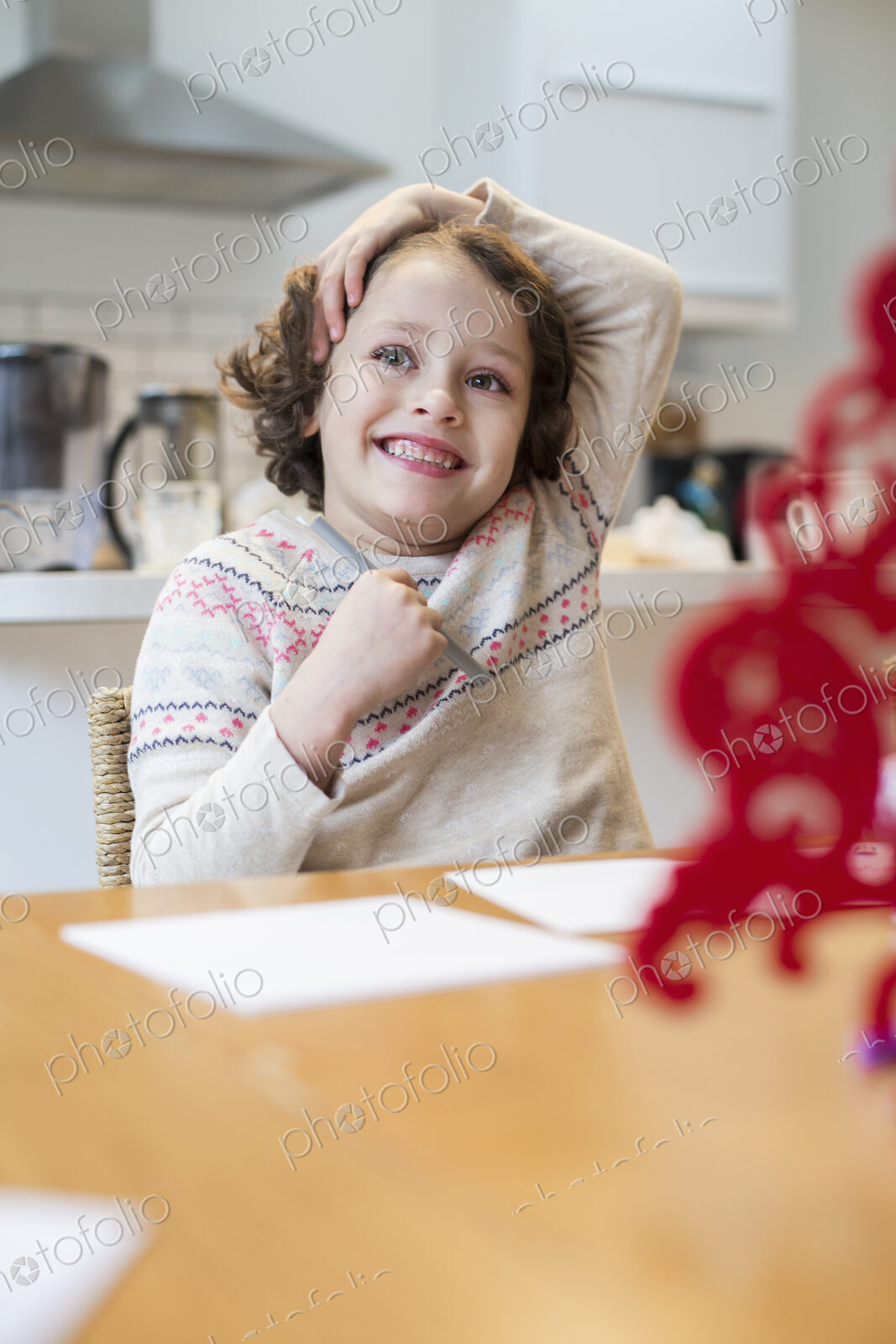 A child, a girl sitting at a table at home, drawing and writing cards before Christmas.