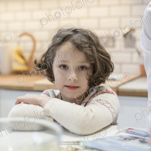A child, a young girl seated at a table, making Christmas cards.