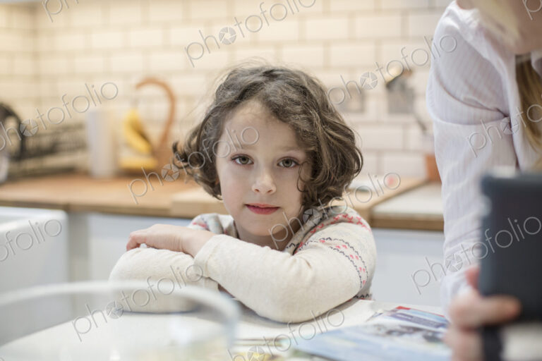 A child, a young girl seated at a table, making Christmas cards.