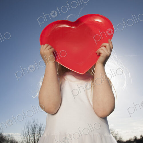 A child holding a red heart shape. A child holding a red heart shape.