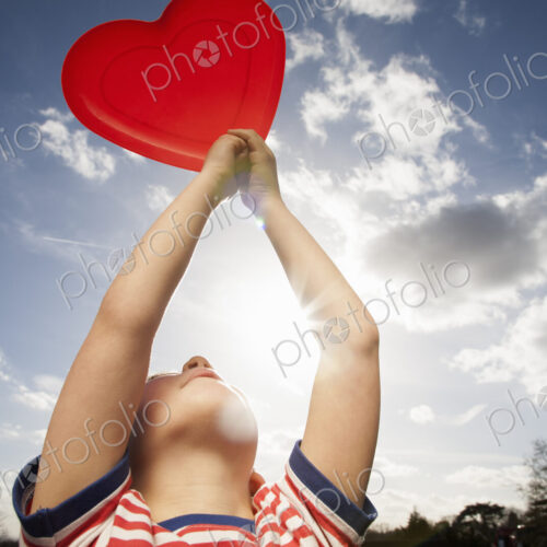 A child holding a red heart shape. A child holding a red heart shape.