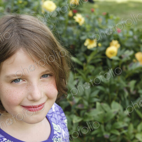 A child in a garden looking up and smiling. A child in a garden looking up and smiling.