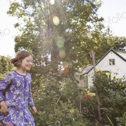 A child in a patterned blue dress running through a house garden. A child in a patterned blue dress running through a house garden.