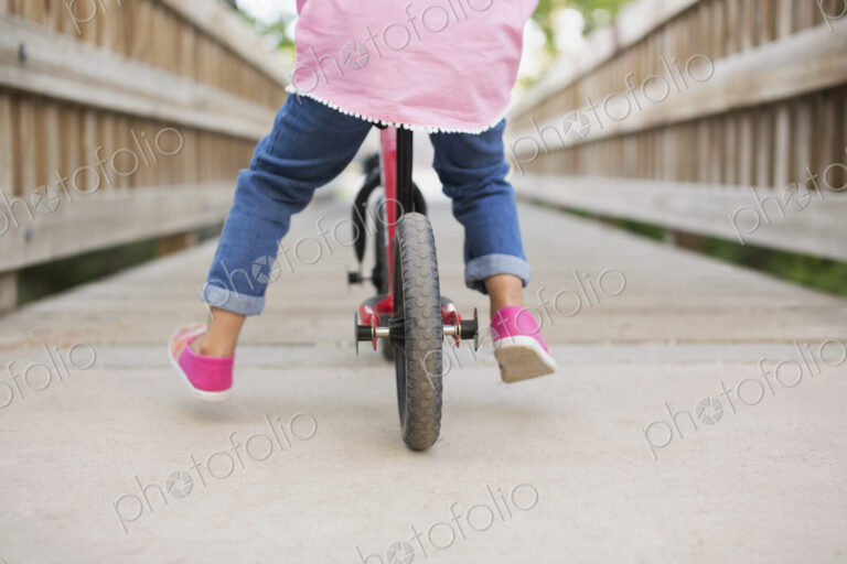 A child riding on a bicycle on a boardwalk.