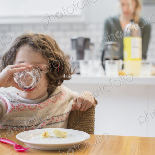 A child sitting at a table drinking from a glass A child sitting at a table drinking from a glass