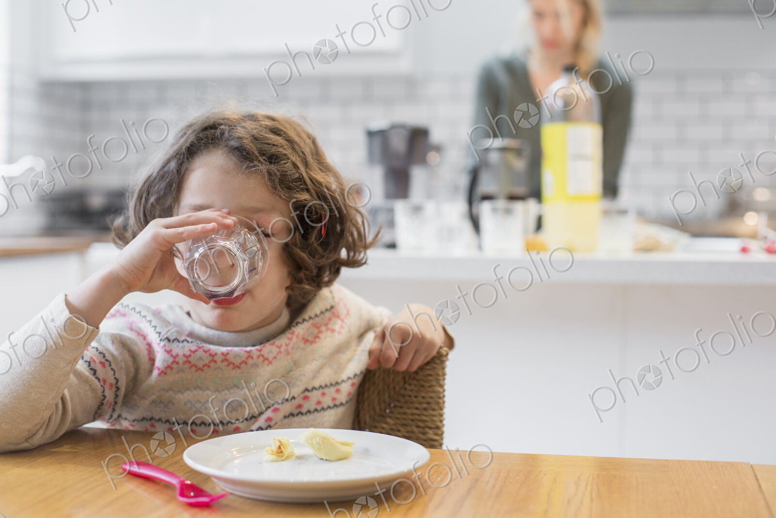 A child sitting at a table drinking from a glass