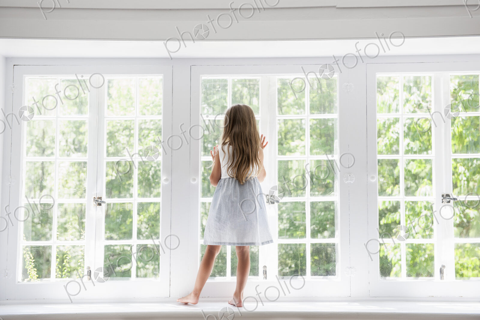 A child standing at a window looking out.