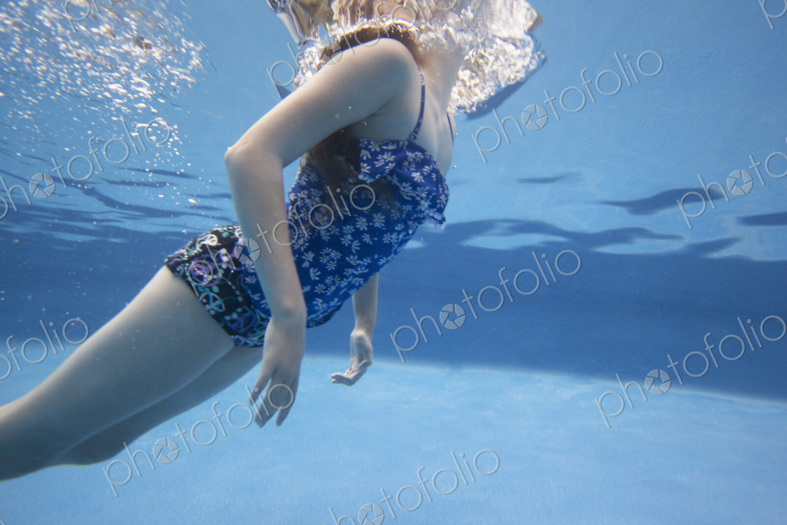 A child swimming under water in a swimming pool.