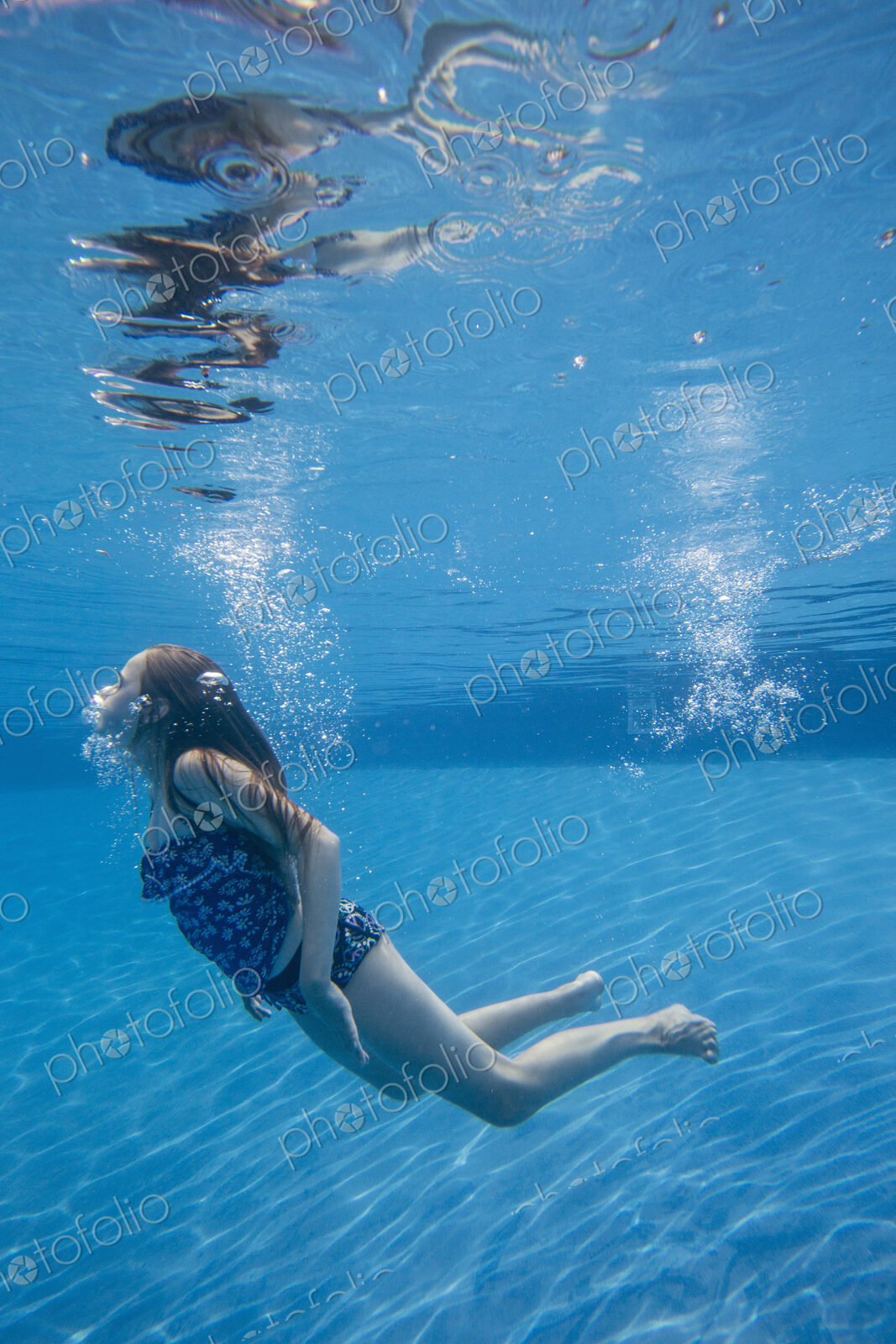 A child swimming under water in a swimming pool.