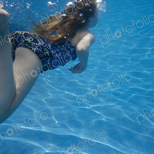 A child swimming under water in a swimming pool. A child swimming under water in a swimming pool.