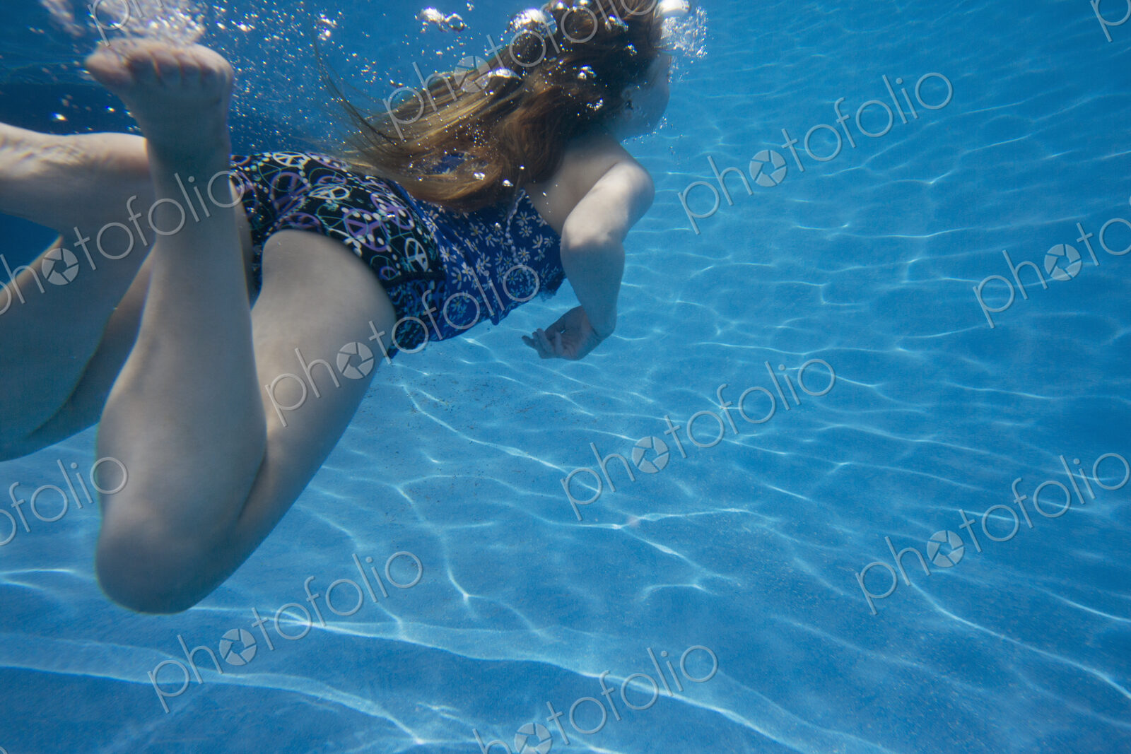 A child swimming under water in a swimming pool.
