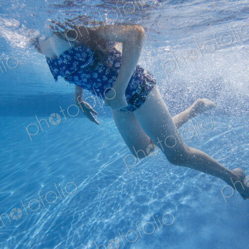 A child swimming under water in a swimming pool. A child swimming under water in a swimming pool.