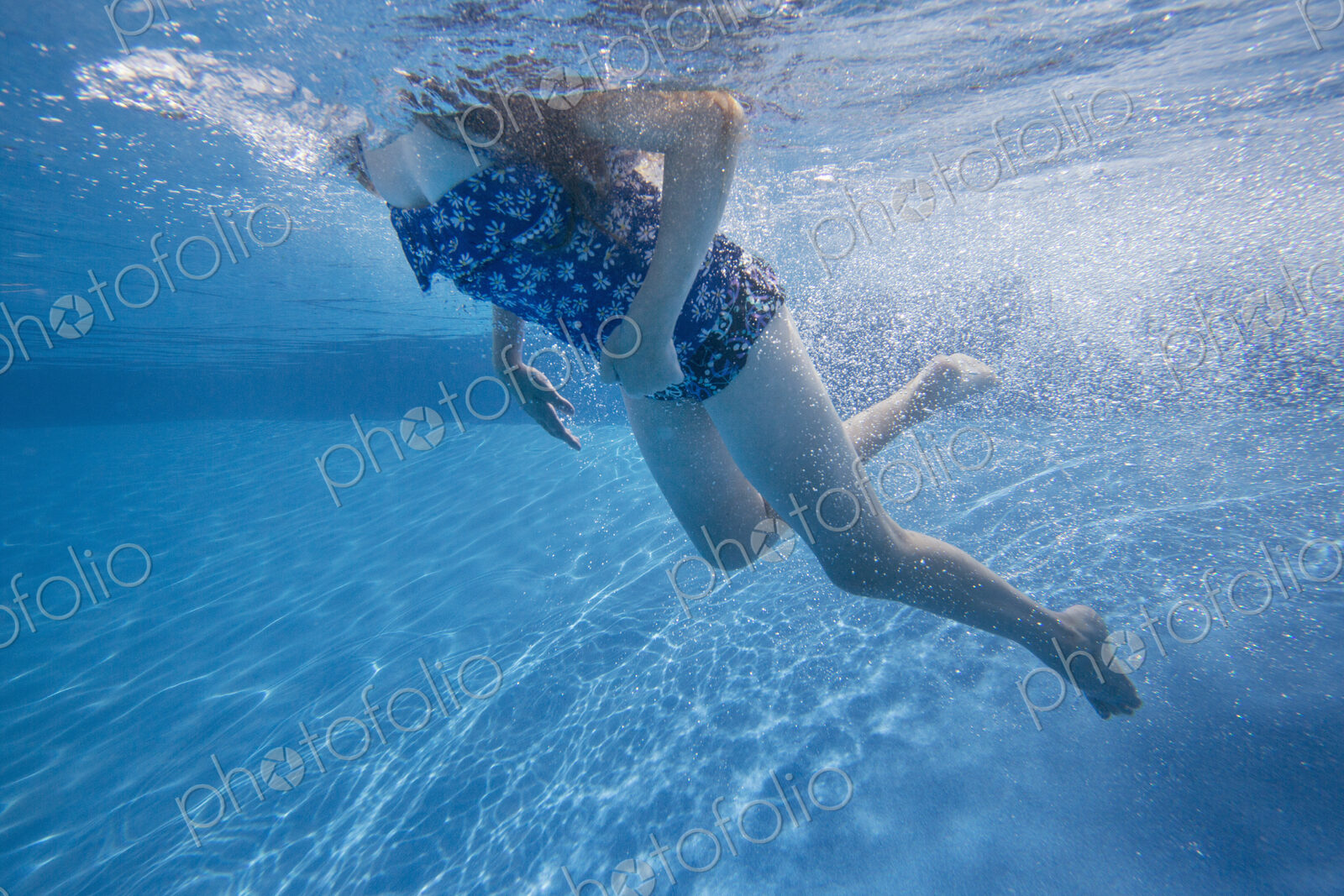 A child swimming under water in a swimming pool.