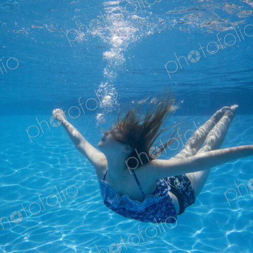 A child swimming under water in a swimming pool. A child swimming under water in a swimming pool.