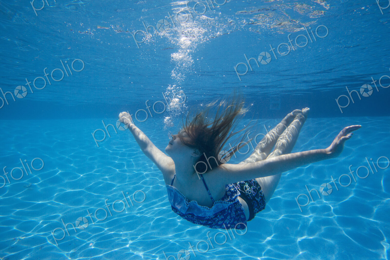 A child swimming under water in a swimming pool.