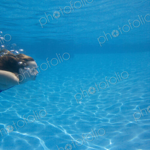A child swimming under water in a swimming pool. A child swimming under water in a swimming pool.