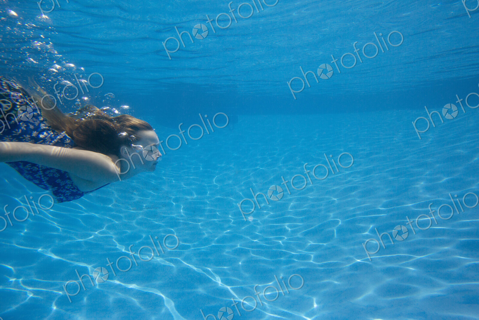 A child swimming under water in a swimming pool.