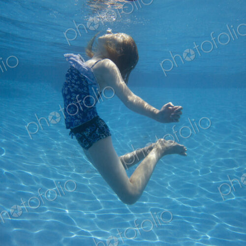 A child swimming under water in a swimming pool. A child swimming under water in a swimming pool.