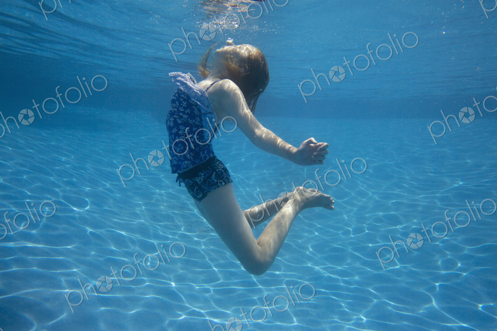 A child swimming under water in a swimming pool.