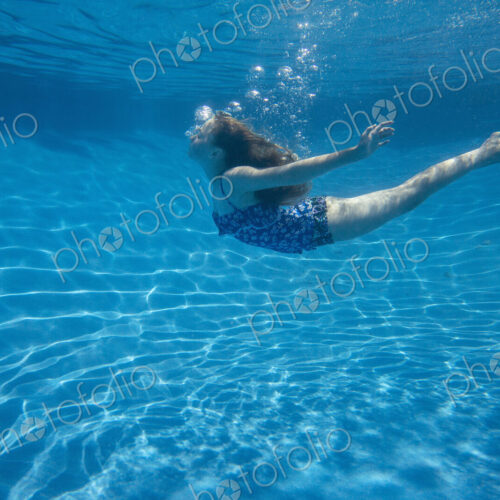 A child swimming under water in a swimming pool. A child swimming under water in a swimming pool.