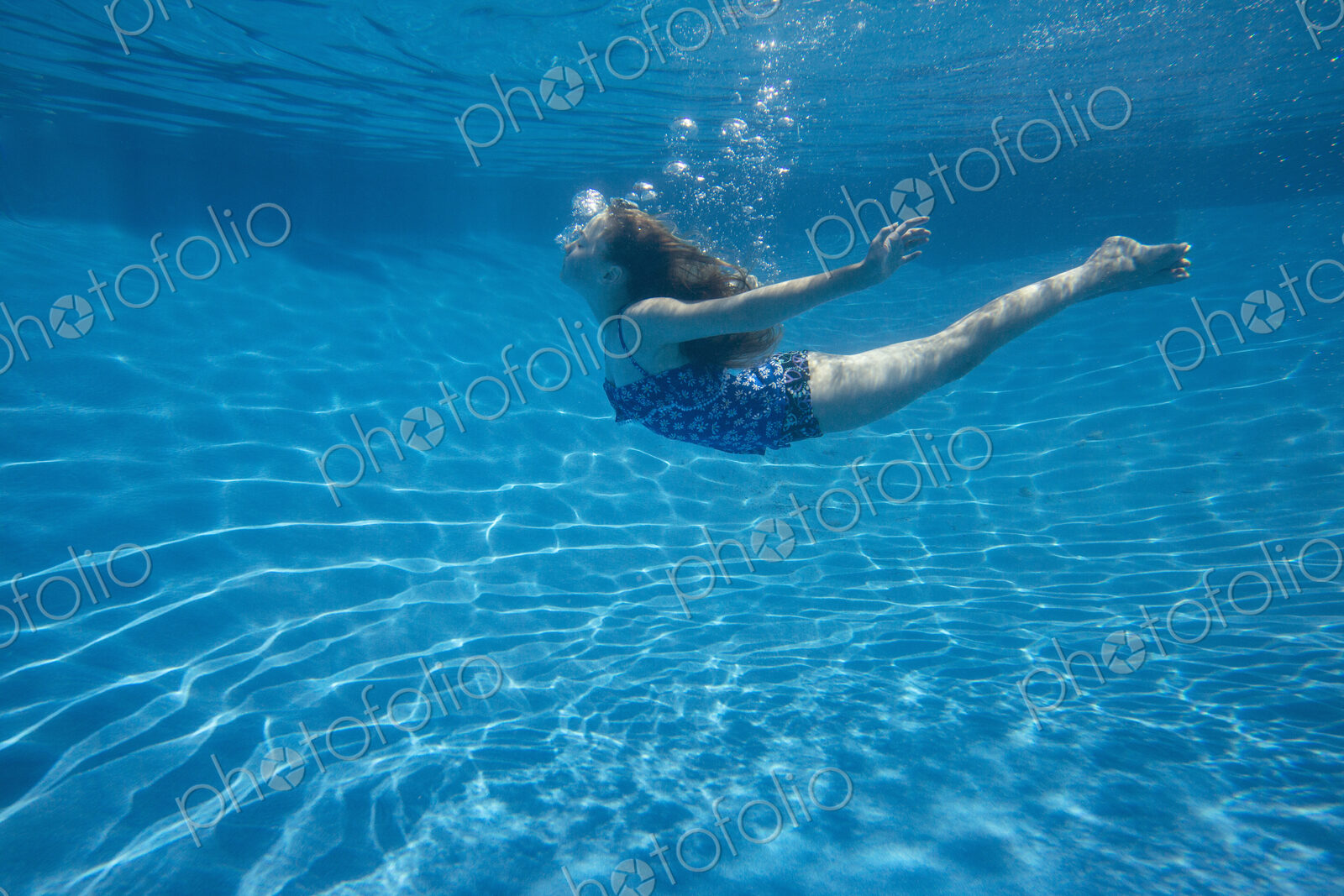A child swimming under water in a swimming pool.