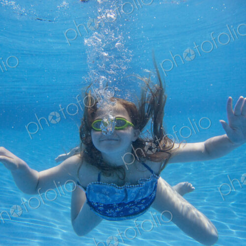 A child swimming under water in a swimming pool. A child swimming under water in a swimming pool.