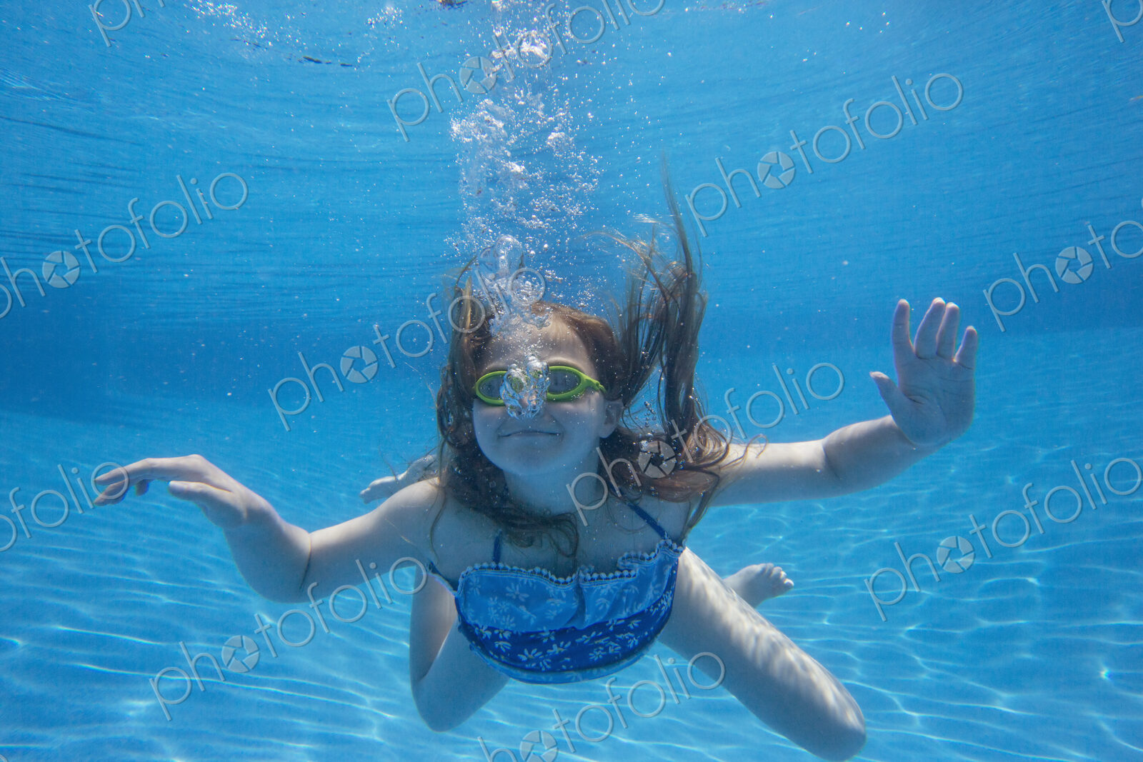 A child swimming under water in a swimming pool.