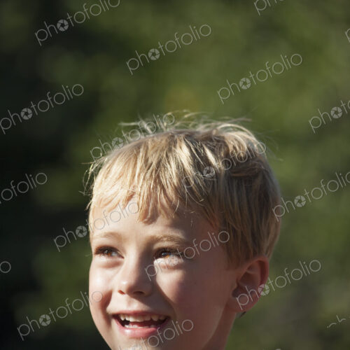A child turning his head to look over his shoulders, smiling.