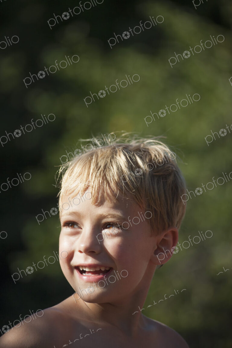 A child turning his head to look over his shoulders, smiling.