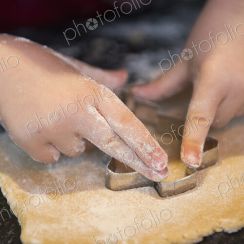 A child using a cookie cutter, making Christmas biscuits.