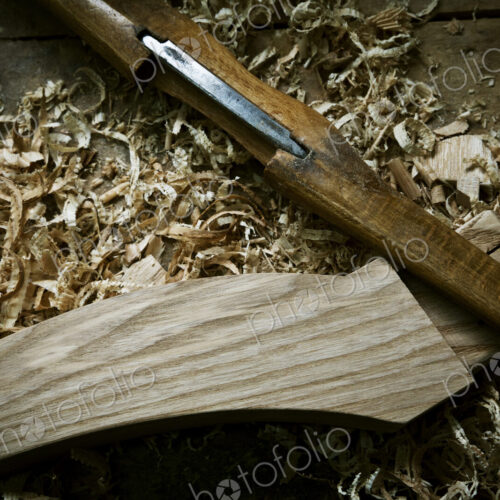 A chisel and wooden object with wood shavings, on a workbench. A chisel and wooden object with wood shavings, on a workbench.