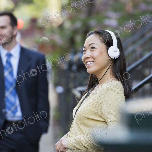 A city street with steps up to the brownstone buildings. A woman wearing music… A city street with steps up to the brownstone buildings. A woman wearing music…