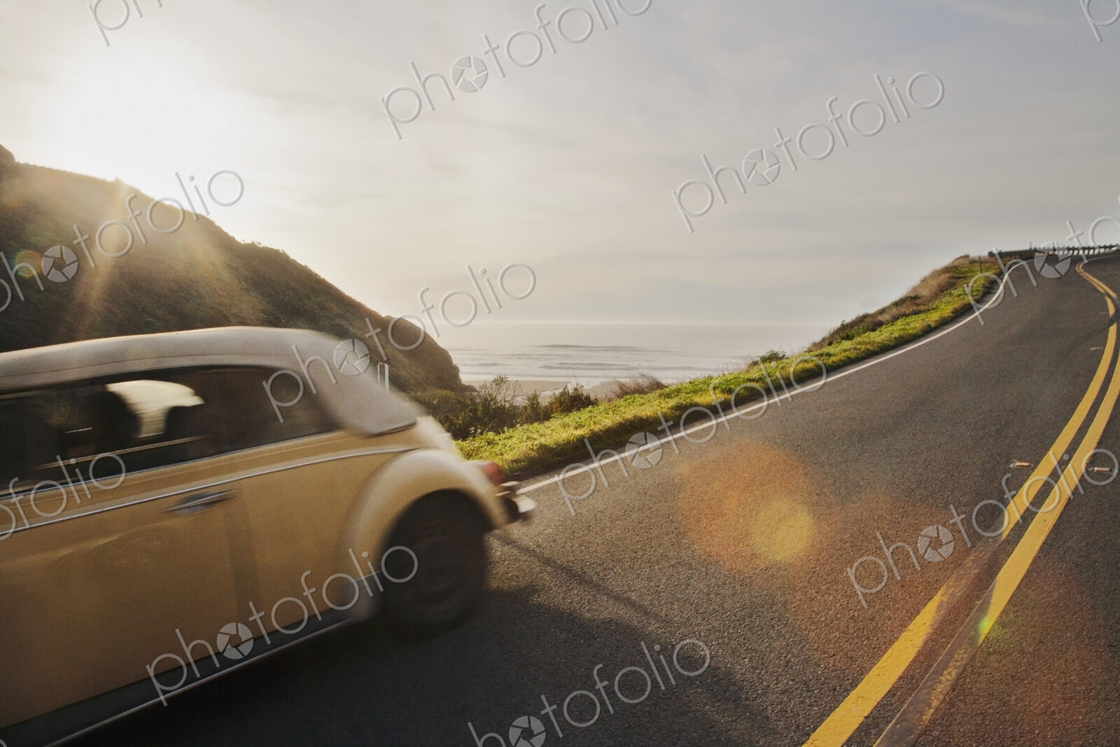 A classic car on a highway along the Pacific coast in the evening light in northern…