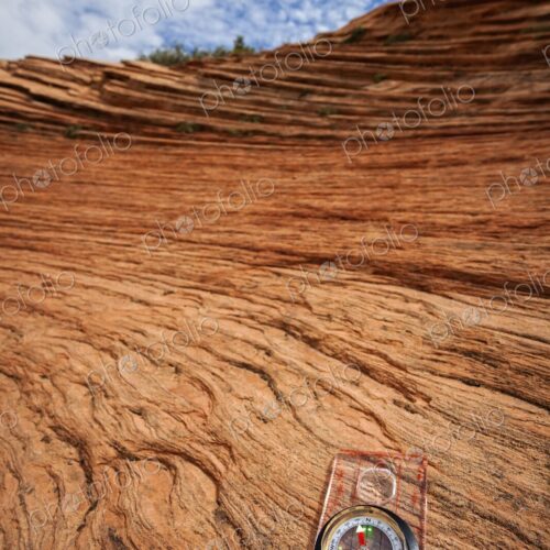 A clear compass rests on weathered red sandstone in Zion National Park, symbolizing… A clear compass rests on weathered red sandstone in Zion National Park, symbolizing…